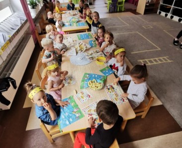 Dzieci z grupy 'Pszczółki' siedzące przy stolikach podczas słodkiego poczęstunku. - powiększ