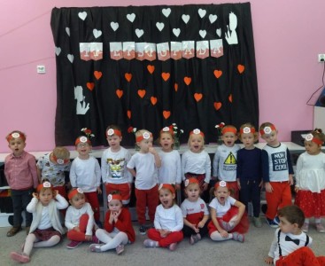 'Pszczółki' na zdjęciu grupowym ubrane w biało-czerwone stroje, na tle napisu '11 listopada' ozdobionego sercami. - powiększ