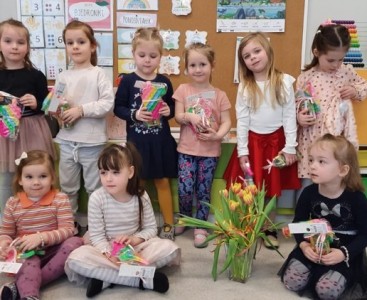 Dziewczynki z grupy 'Biedronki' na zdjęciu z kwiatami oraz upominkami.  - powiększ