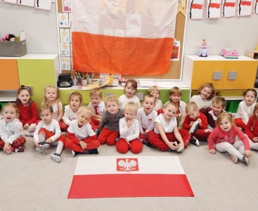 'Biedronki' na zdjęciu grupowym w biało-czerwonych barwach z Flagą Polski w tle. - powiększ
