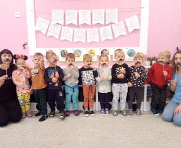 Zdjęcie grupowe dzieci z podarunkami w formie wąsików. - powiększ