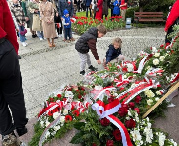 Dzieci składają kwiaty pod pomnikiem Ofiarom Wojen i Przemocy - powiększ