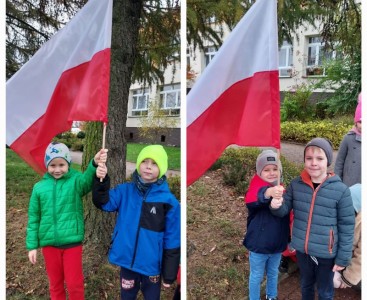 Dzieci w parach przed przedszkolem dumnie prezentują flagę Polski. - powiększ