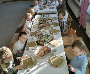 Wspólne śniadanie 'Pszczółek'. Na zdjęciu dzieci siedzą przy wspólnym stole i jedzą śniadanie. - powiększ