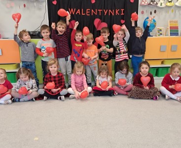 'Liski' na zdjęciu grupowym na tle napisu 'Walentynki'. Dzieci trzymają przed sobą otrzymane prezenty walentynkowe - lizaki i balony w kształcie serca. - powiększ